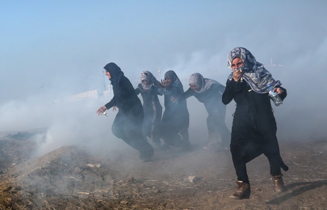 Người biểu tình Palestine chạy trốn khỏi khu vực hơi cay trong cuộc xung đột với binh lính Israel tại biên giới Gaza-Israel ngày 15/5. (Nguồn: EPA/TTXVN)