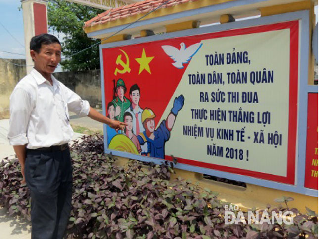 Trưởng thôn Nguyễn Đố bên bảng tuyên truyền do các hội viên chi hội Cựu chiến binh thôn Nhơn Thọ 2 thực hiện.
