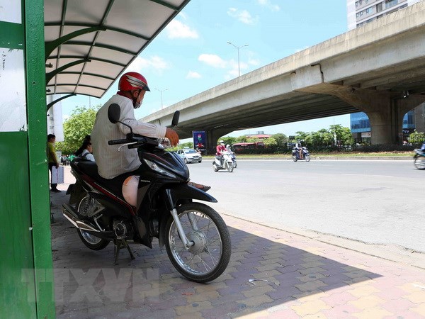 Người hành nghề xe ôm tránh nắng ở bến xe buýt trên tuyến đường Phạm Hùng. (Ảnh: Thành Đạt/TTXVN)