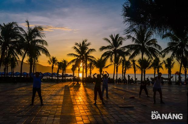 Local residents are bathing with the first glimmering rays of sunlight whilst doing physical exercise on a beach in an early morning