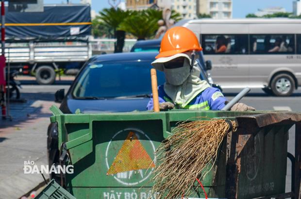 A female sanitation worker working under the scorching sun