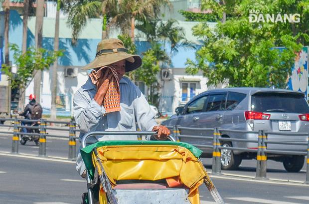 A cyclo driver wiping the sweat from his face