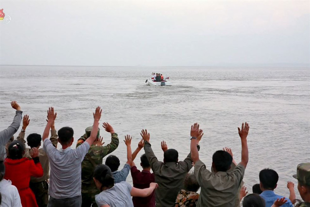 Những người dân tại Sindo vẫy tay chào ông Kim Jong-un khi xuồng chở nhà lãnh đạo Triều Tiên quay trở về đất liền sau chuyến thị sát.