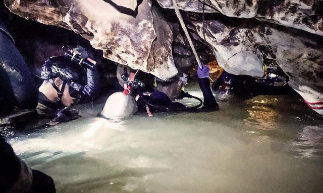 Các thợ lặn bám dây thừng lội qua lối đi ngập nước trong hang Tham Luang (Ảnh: Nation)