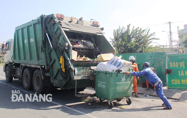 Sanitation workers collecting uploading garbage onto trucks on Tran Thanh Tong Street 