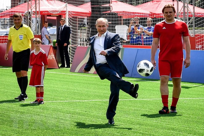 Tổng thống Nga Vladimir Putin (giữa) sút bóng khi ông tham dự lễ khai mạc triển lãm trận đấu bóng đá tại Công viên bóng đá World Cup trên Quảng trường Đỏ ở thủ đô Moskva ngày 28/6. (Ảnh: AFP/TTXVN)