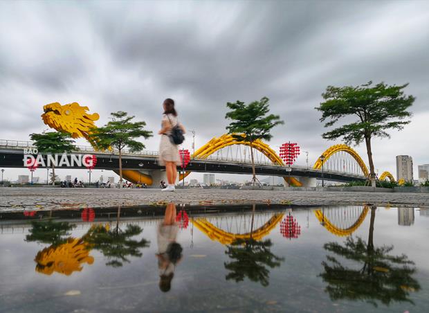 The reflection of the Rong (Dragon) Bridge in a water puddle on Tran Hung Dao  after the rain