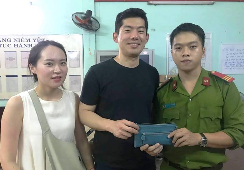 A police officer returning missing property to the Korean visitors (Photo: http://cand.com.vn)