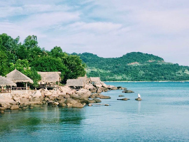 Several palm leaf huts are built on large stones in Bai Rang