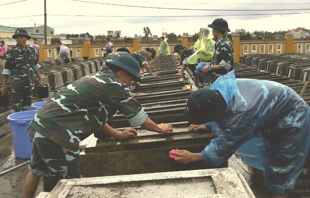 Soldiers from Battalion No 179 of the Air Defense and Air Force Regiment No 282 cleaning old graves in the Hoa Chau Commune Martyrs’ Cemetery