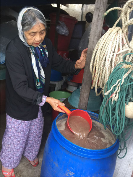 Bà Trần Thị Ngưng kiểm tra chất lượng thùng nước mắm trước khi lọc. 