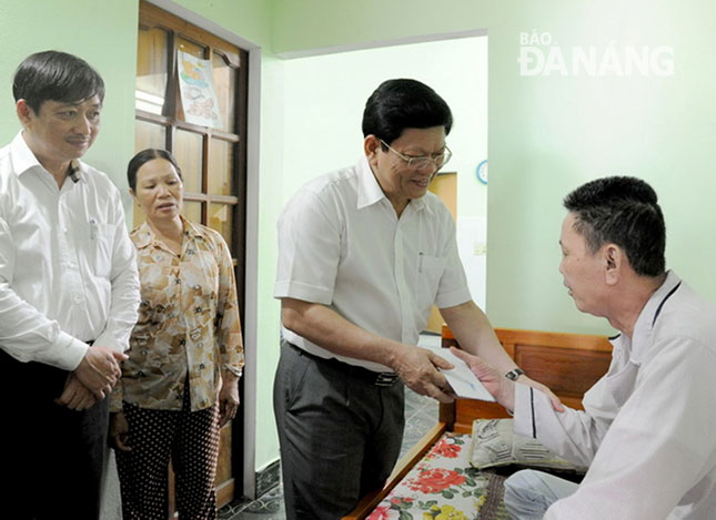 Municipal Party Committee Deputy Secretary Vo Cong Tri (2nd right) and People’s Committee Vice Chairman Dang Viet Dung (1st left) presenting a gift to a social policy beneficiary. 