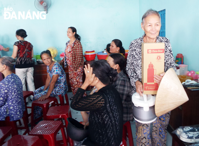 A senior woman receiving free-of-charge electric cooker and thermos flask at the fair