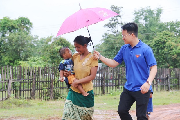 A Da Nang volunteer shading a woman with an umbrella under the rain