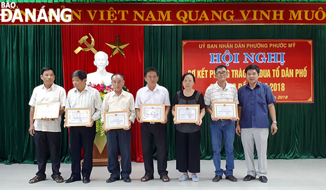 Ông Đinh Công Bộ (thứ hai từ trái qua) nhận giấy khen của phường Phước Mỹ tại buổi sơ kết phong trào thi đua tổ dân phố 6 tháng đầu năm 2018.