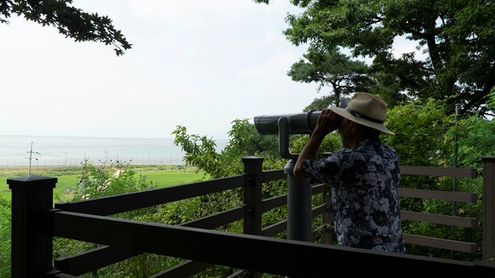Ông Hwang dùng một cặp ống nhòm để nhìn về phía Triều Tiên. Ảnh: Reuters.