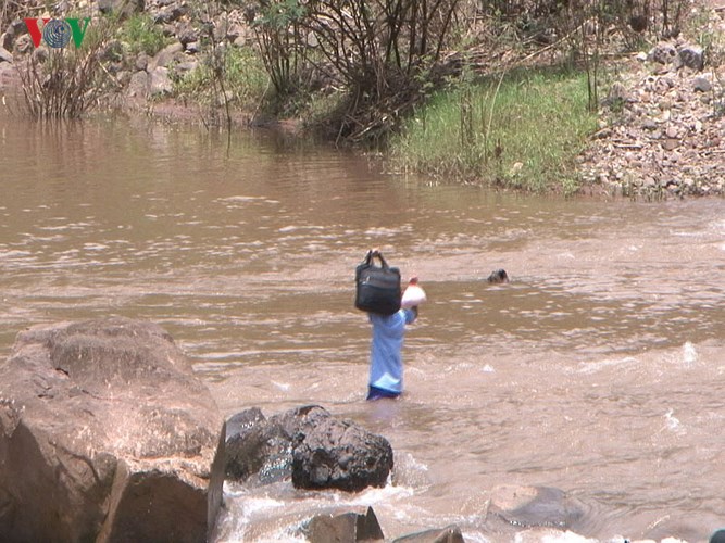 Những học sinh nam cố một mình tự vượt sông khi nước lặng.