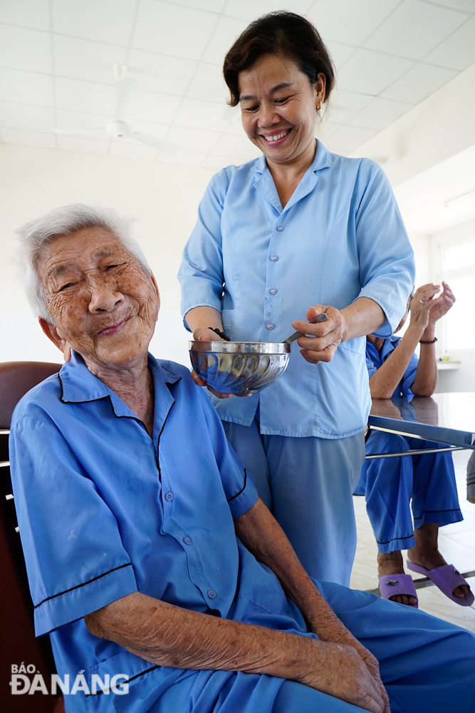 An elderly citizen is being fed by a staff member