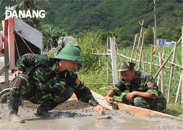 Trung úy Mai Thanh Tài (bên trái) tham gia giúp dân làm đường  bê-tông nông thôn tại thôn Nam Yên, xã Hòa Bắc. 