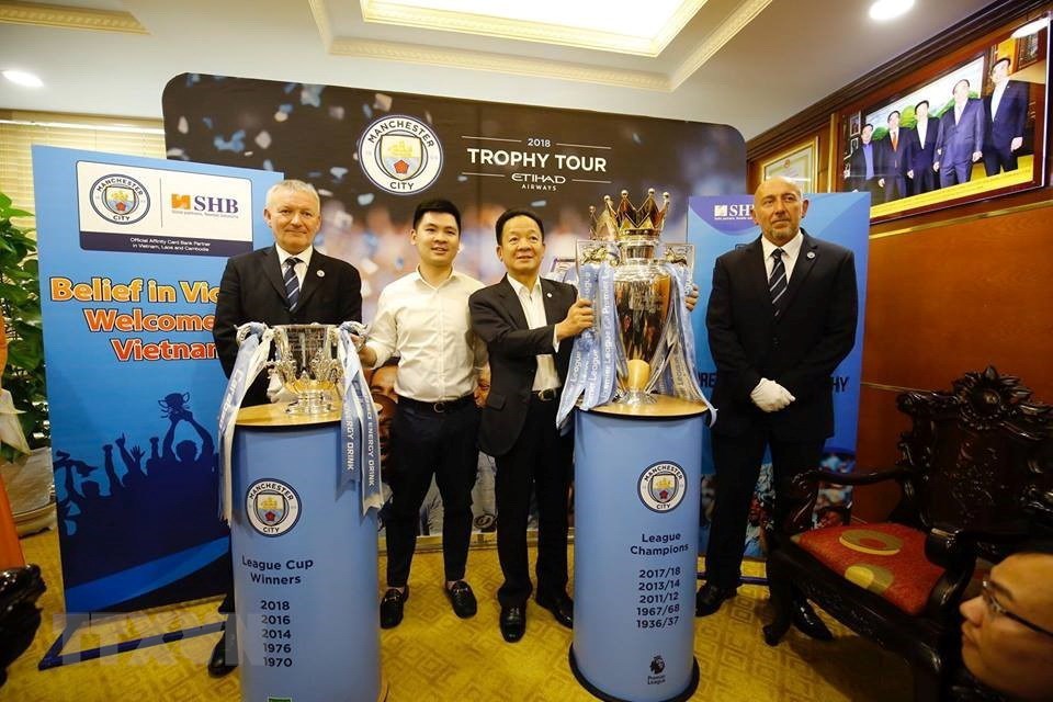 Ông Đỗ Quang Hiển, Chủ tịch Hội đồng quản trị kiêm Tổng Giám đốc Tập đoàn T&T Hà Nội bên cạnh hai chiếc cúp mà câu lạc bộ Manchester City đã giành được trong mùa giải 2017/2018. (Nguồn: TTXVN)