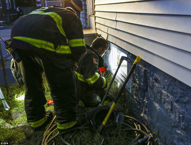 Các nhân viên cứu hỏa tìm cách vào một ngôi nhà thông qua tầng hầm để kiểm tra đường ống gas tại thị trấn Lawrence.