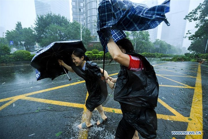 Hai người phụ nữ khom người bước đi trong mưa bão ở Thâm Quyến, Quảng Đông, Trung Quốc. Ảnh: Tân Hoa xã.