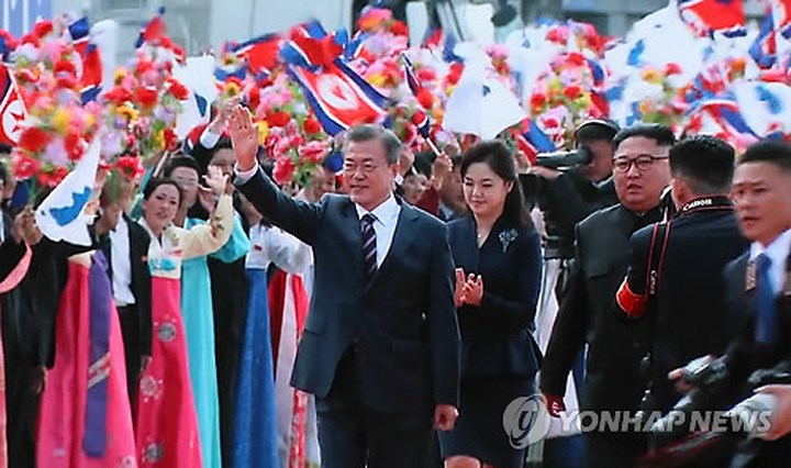 Tổng thống Hàn Quốc Moon Jae-in (trái) sánh bước cùng nhà lãnh đạo Triều Tiên Kim Jong-un (phải) và vẫy chào những người có mặt tại sân bay quốc tế Sunan ở Bình Nhưỡng ngày 18/9/2018.