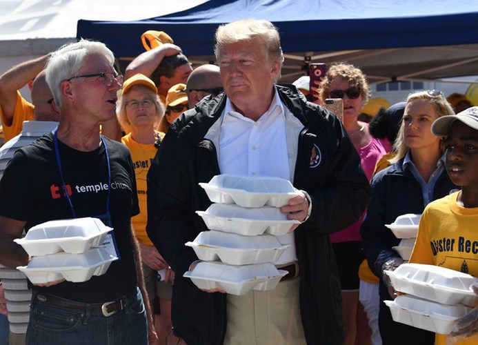 Ông Trump cầm trên tay các hộp đồ ăn để phát cho người dân.