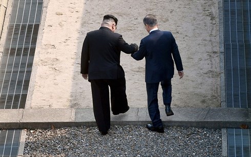 Ông Kim Jong-un nắm tay ông Moon Jae-in bước qua đường ranh giới giữa 2 nước để sang lãnh thổ Triều Tiên trong lần gặp đầu tiên giữa 2 nhà lãnh đạo. (Ảnh: Bloomberg)