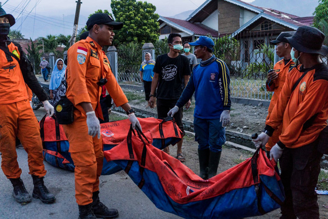 Đội cứu hộ vận chuyển túi đựng các thi thể nạn nhân sau thảm họa kép. (Ảnh: New York Times)