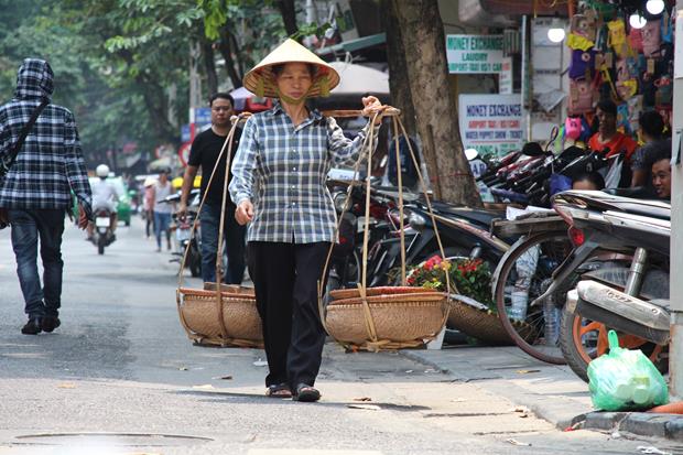 A woman holding a set of Quang Ganh on a street