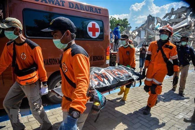 Rescue members transfer a body at a collapsed hotel in Palu, Central Sulawesi, Indonesia. (Photo: Xinhua/ VNA)