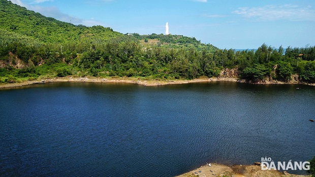 The lake is clear and dark blue. From there, visitors can see the Avalokitecvara Buddha Statue standing at the Linh Ung Pagoda.