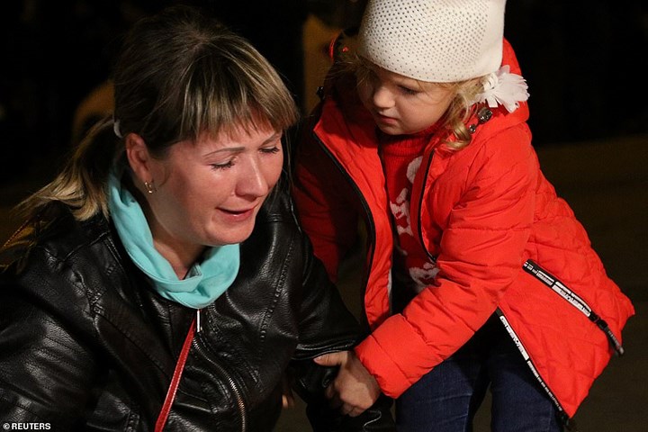 Một bé gái đang an ủi một người phụ nữ tại nơi tưởng niệm các nạn nhân ở Kerch, Crimea. Ảnh: Reuters.
