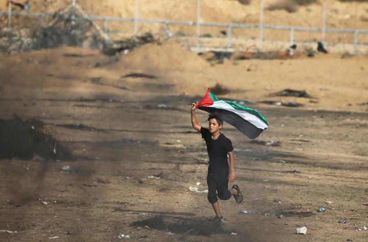Một đứa trẻ cầm cờ Palestine tham gia biểu tình.