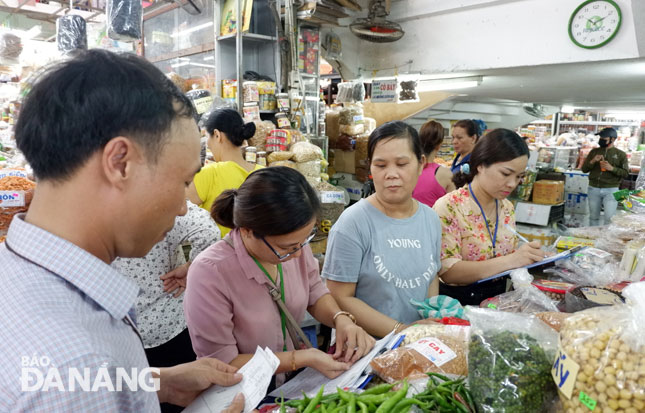 Lực lượng chức năng lấy mẫu ớt bột tại các chợ trên địa bàn thành phố để kiểm tra việc sử dụng các loại chất cấm trong bảo quản, chế biến thực phẩm.  Ảnh: PHAN CHUNG