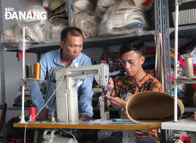 Tạo ra các sản phẩm làm từ cói cũng là một quá trình sáng tạo không ngừng. Trong ảnh: Anh Văn Hồng Hải (trái) đang hướng dẫn, góp ý cho lao động hoàn thiện sản phẩm túi làm từ cói.
