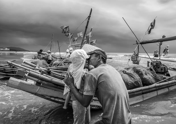 A fisherman kissing his daughter on the forehead