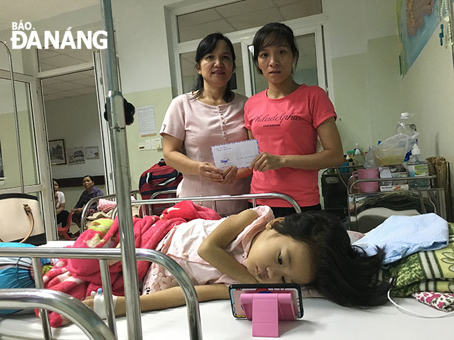 Đại diện Sở LĐ-TB&XH (bên trái) trao số tiền 10 triệu đồng của UBND thành phố cho mẹ cháu Lê Hoàng Huyền Tra.
