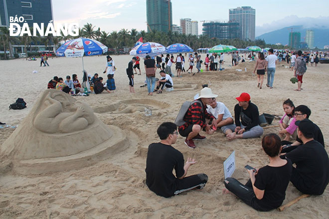 Du khách phấn khích nhìn ngắm những tượng cát trên bãi biển Phạm Văn Đồng, một hoạt động trong chương trình Mùa du lịch biển 2018.