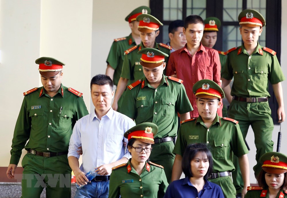 Bị cáo Phan Sào Nam (áo trắng) cùng các bị cáo được cơ quan chức năng dẫn giải ra tòa. (Ảnh: Trung Kiên/TTXVN)