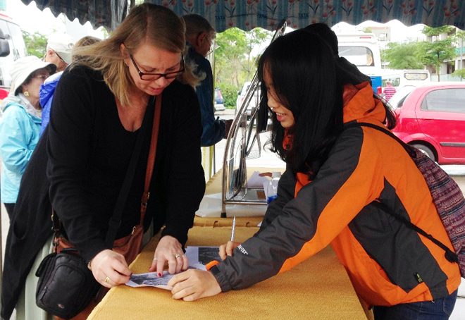 A volunteer providing a foreign cruise ship passenger (left) with information relating to the city’s popular tourist attractions.