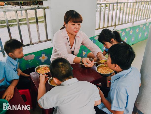 A female teacher spoon-feeding her pupils.