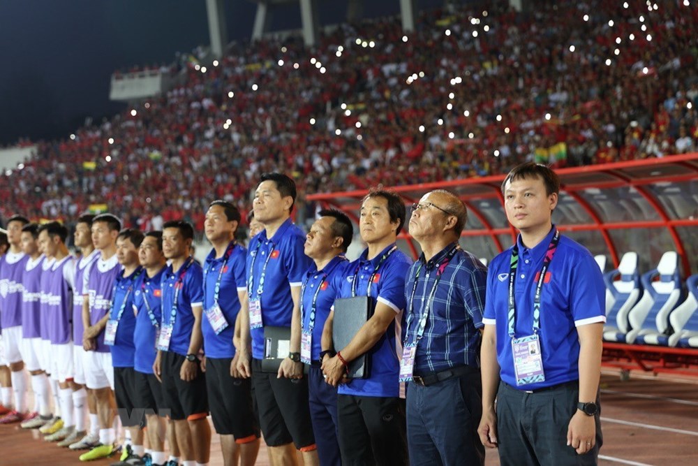 Ban huấn luyện và các cầu thủ dự bị của đội tuyển Việt Nam thực hiện nghi thức chào cờ. (Ảnh: Trọng Đạt/TTXVN)