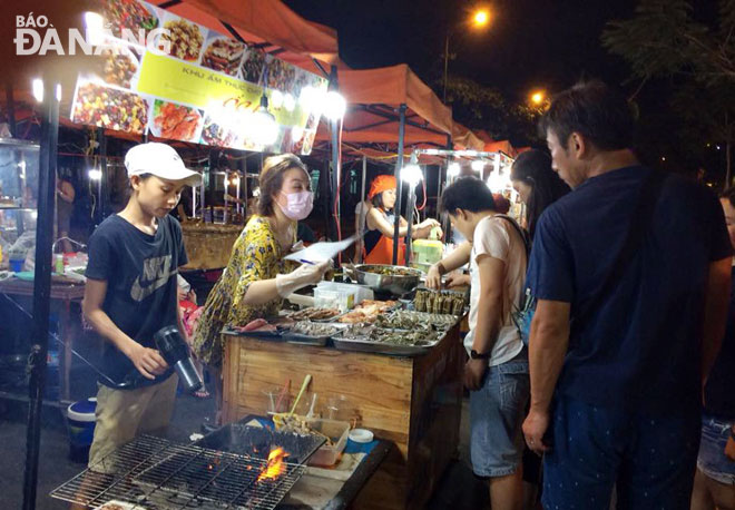 Khách du lịch Hàn Quốc tò mò với các món nướng hải sản tại chợ đêm Sơn Trà. Ảnh: Đ.H.L