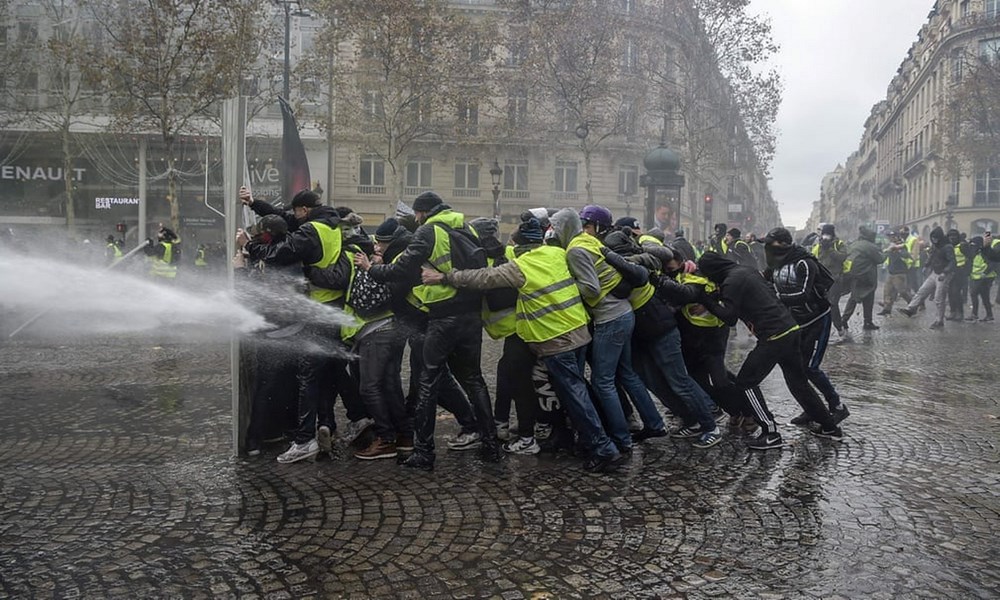 Những người biểu tình của phong trào 'áo vàng' chống chọi với vòi rồng của lực lượng an ninh Pháp. (Nguồn: AFP)