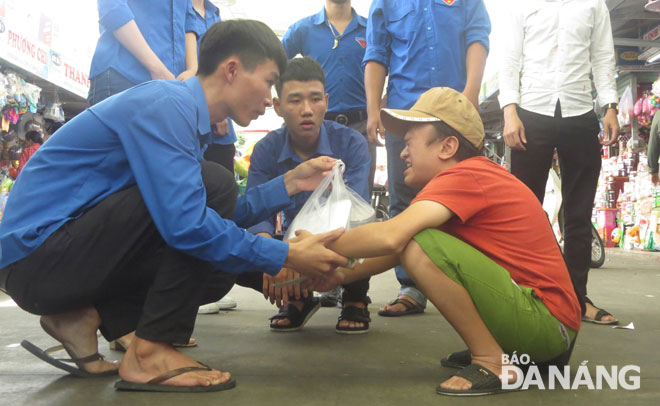 Sinh viên đội tình nguyện Trường Đại học Kiến trúc Đà Nẵng và Trường Cao đẳng FPT tham gia nấu cơm (hình 1) và phát cơm cho người dân lao động nghèo (hình 2).