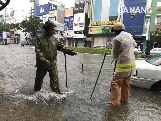 Local traffic police unblocking a sewer on a flooded road