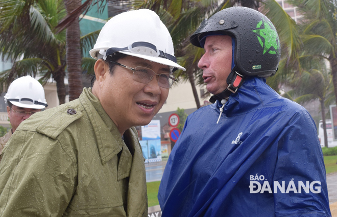 Chủ tịch UBND thành phố (bìa trái) chuyện trò và trấn an du khách nước ngoài về tình hình mưa lớn tại thành phố.