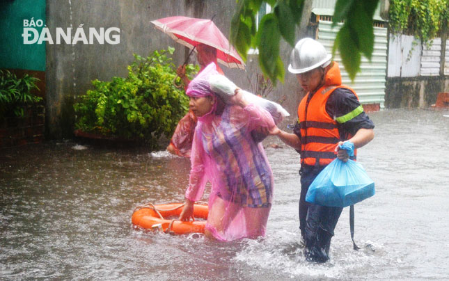 Lực lượng chức năng sơ tán người dân ở khu vực trũng thấp tại phường Hòa Thuận Tây, quận Hải Châu đến nơi trú ẩn an toàn. 				  Ảnh: XUÂN SƠN